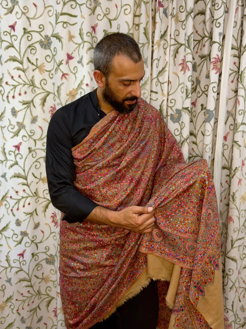 A House of Kais shawl, its intricate paisley craftsmanship worn and held in view